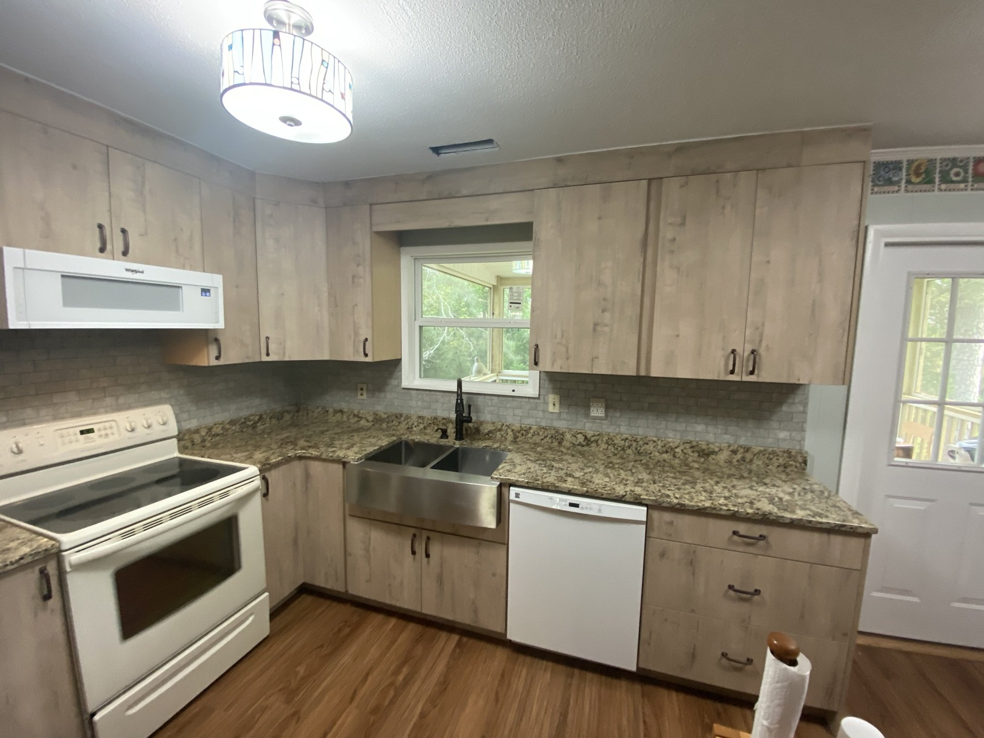 Driftwood finish slab door cabinets with granite counters and a stainless farmhouse sink