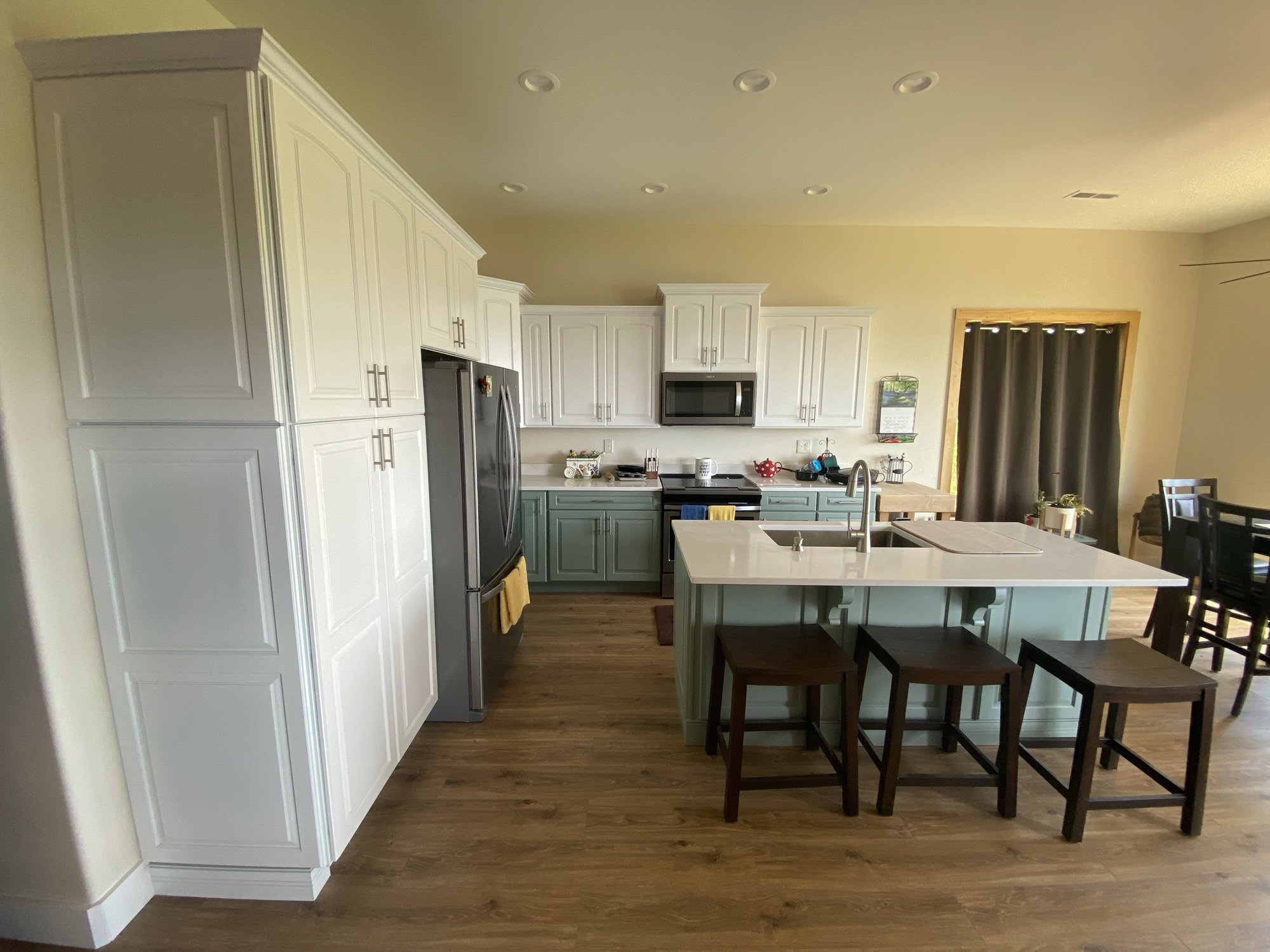 Kitchen with white upper cabinets, sage green base cabinets, and a quartz island