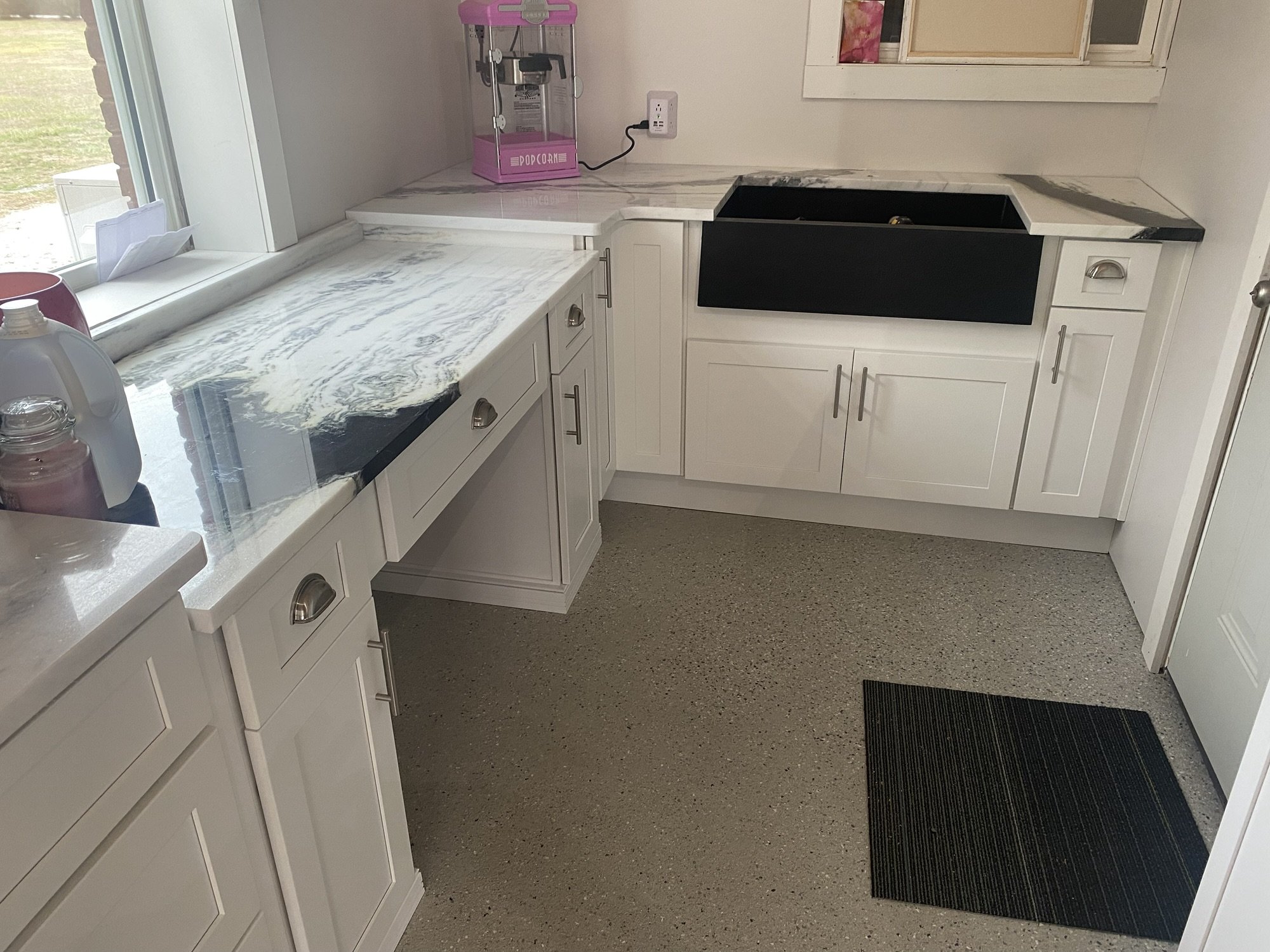 White cabinets with dramatic black and white marble countertops and a black farmhouse sink