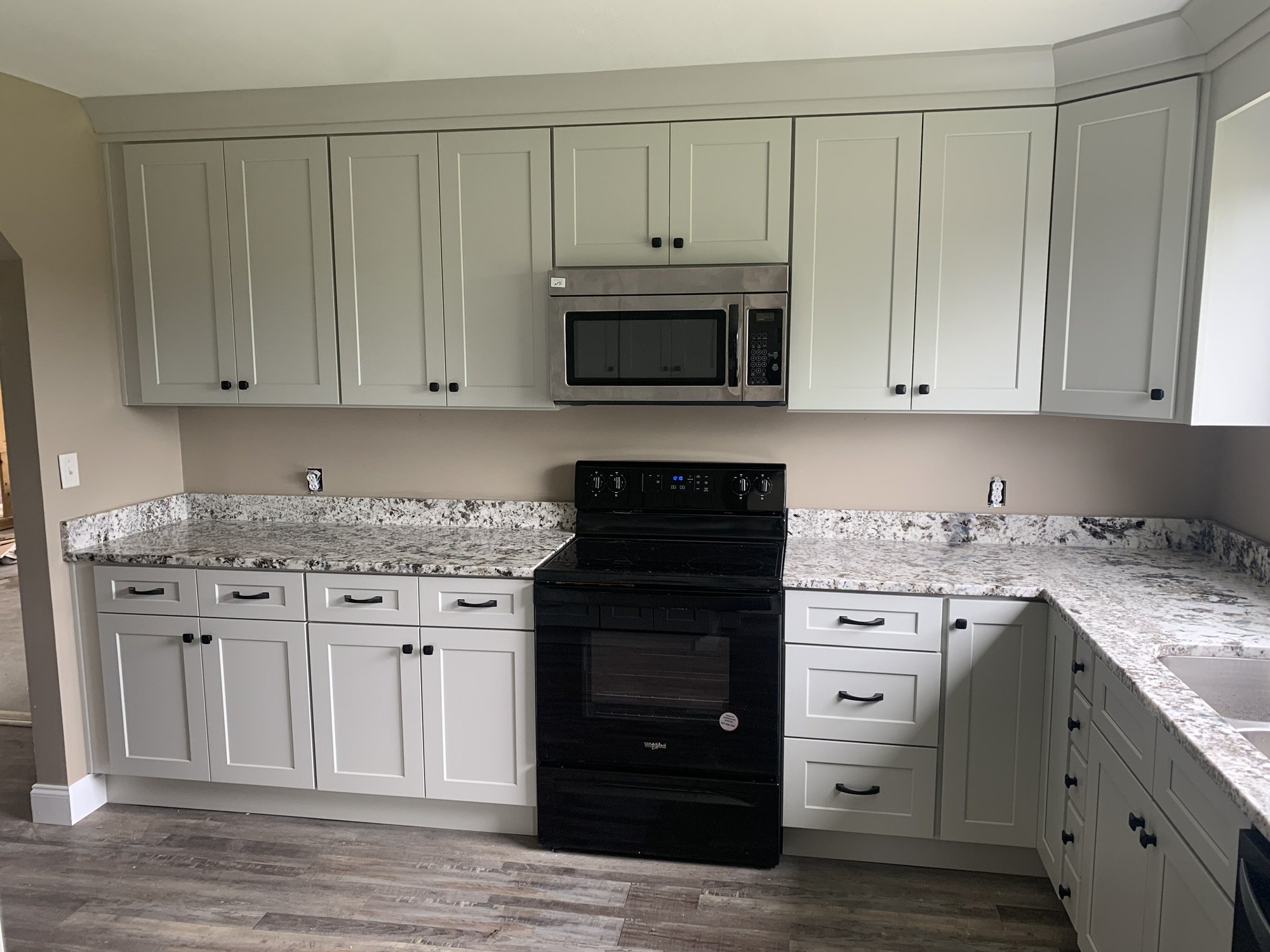 Sage green shaker kitchen cabinets with white and black speckled granite countertops