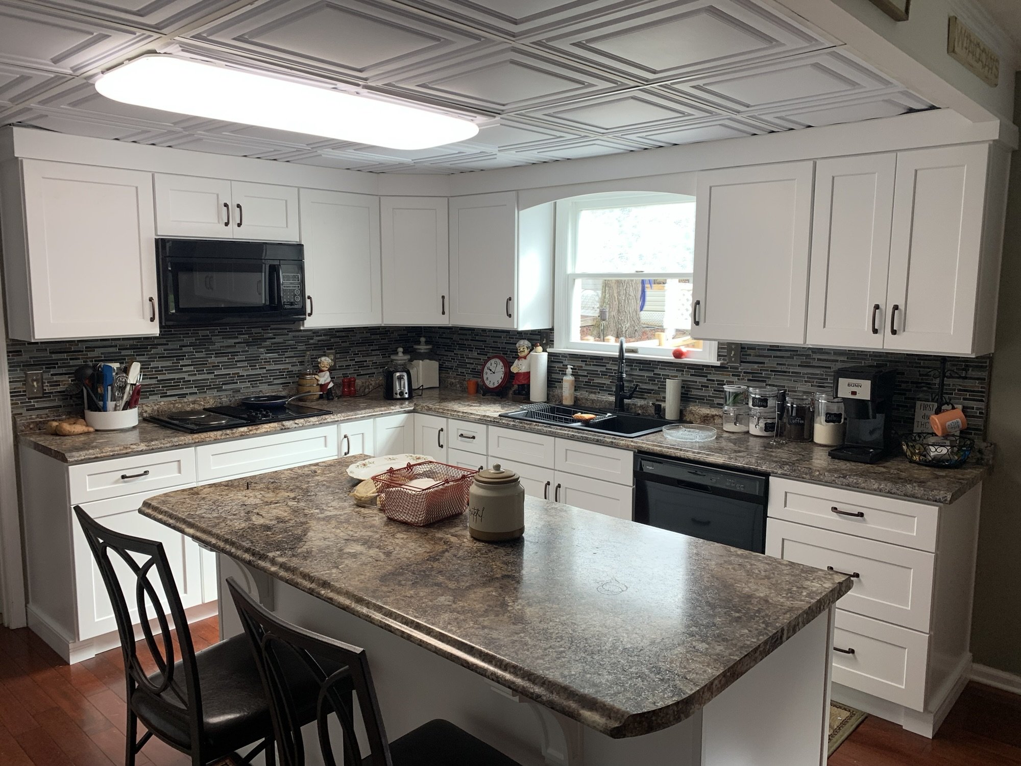 White shaker kitchen with a glass mosaic backsplash and a large seated island