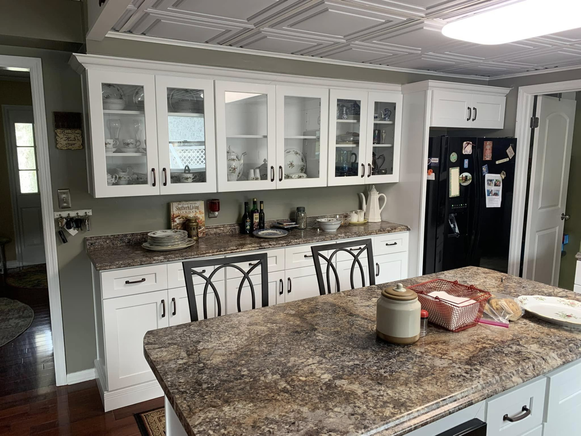White glass front display cabinets with a granite counter and island
