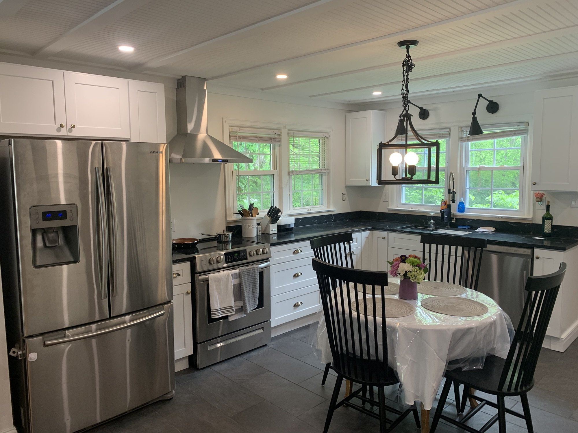 White kitchen cabinets with black stone countertops and slate tile flooring