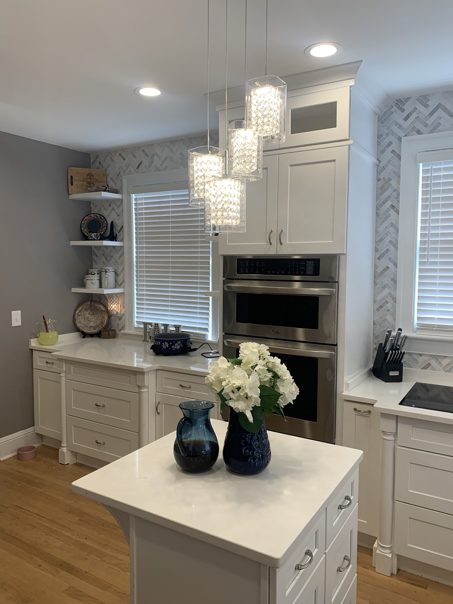 Cream kitchen cabinets with white quartz counters and a herringbone marble tile backsplash
