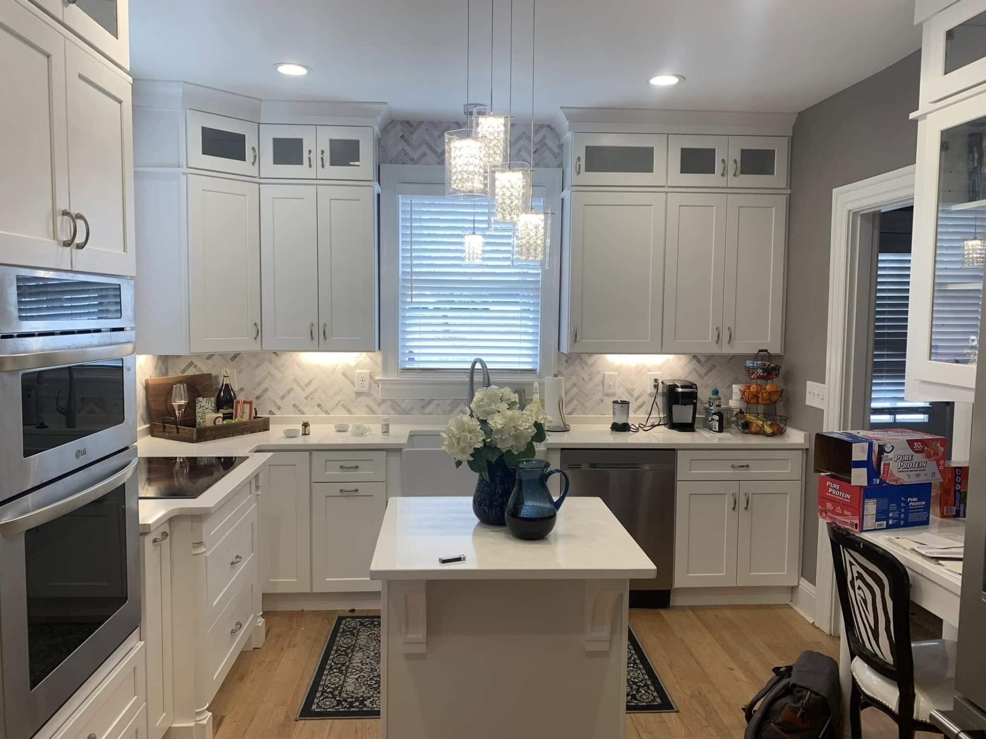 White kitchen with herringbone marble backsplash, quartz counters, and a small island