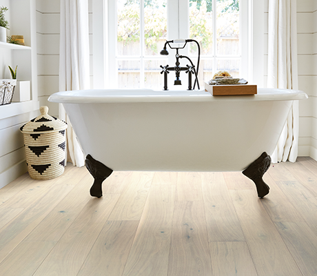 White bathtub in a bathroom with wood-look luxury vinyl flooring from Value Flooring Kitchens & Baths in Cleveland, TN